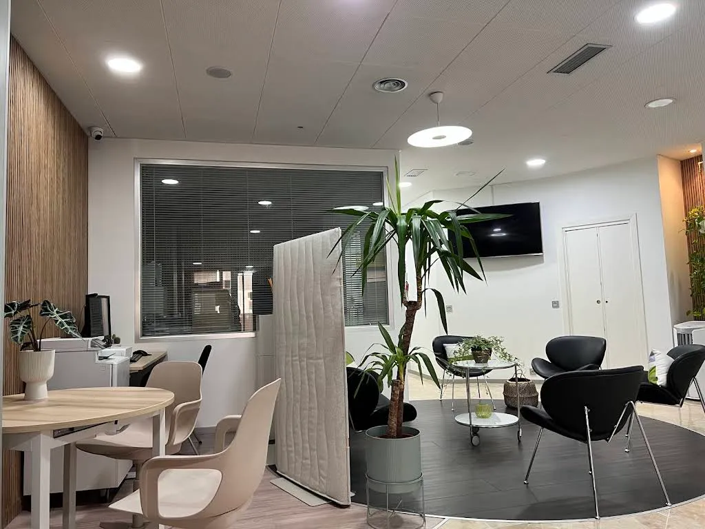 Sala de espera de Odontología Integrada Clínicas Dentales, con butacas, plantas y luz cálida