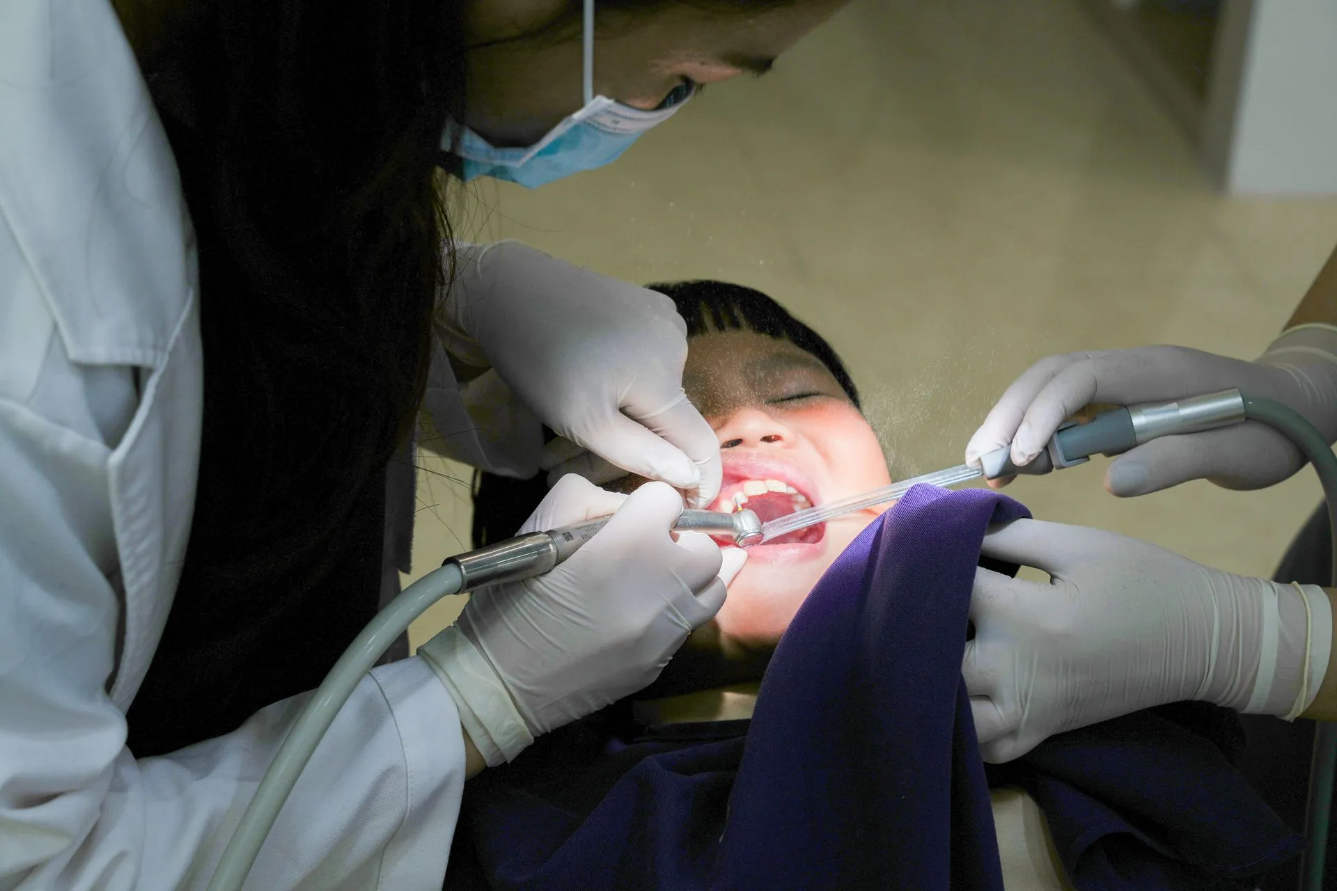 Dentistas atendiendo a un niño en el sillón dental durante una revisión