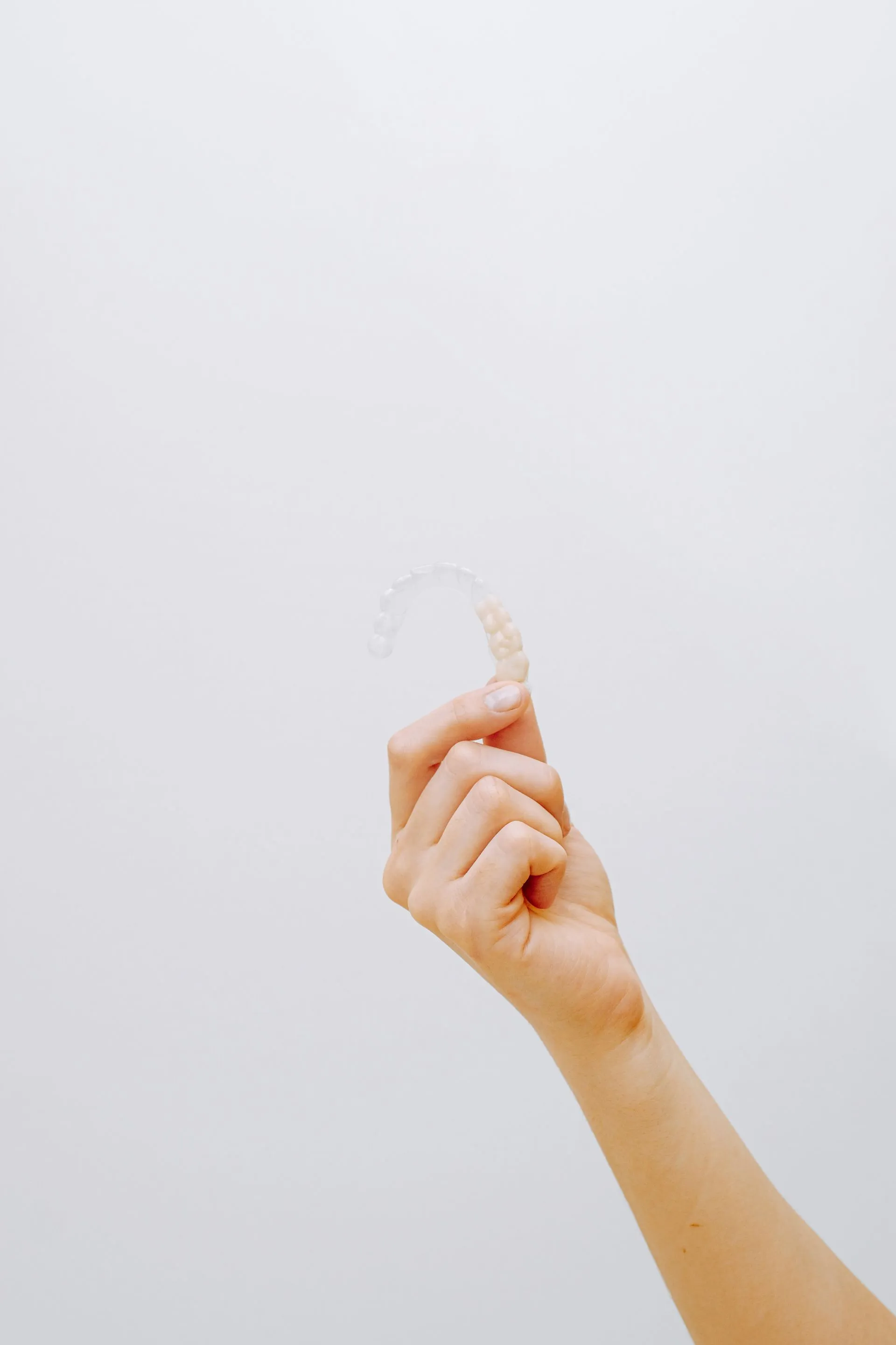 Mano sosteniendo un alineador dental transparente removible