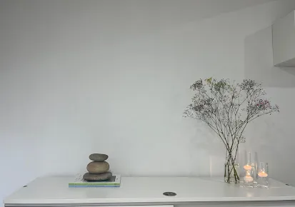 Detalle minimalista de la recepción de la clínica, con flores y velas